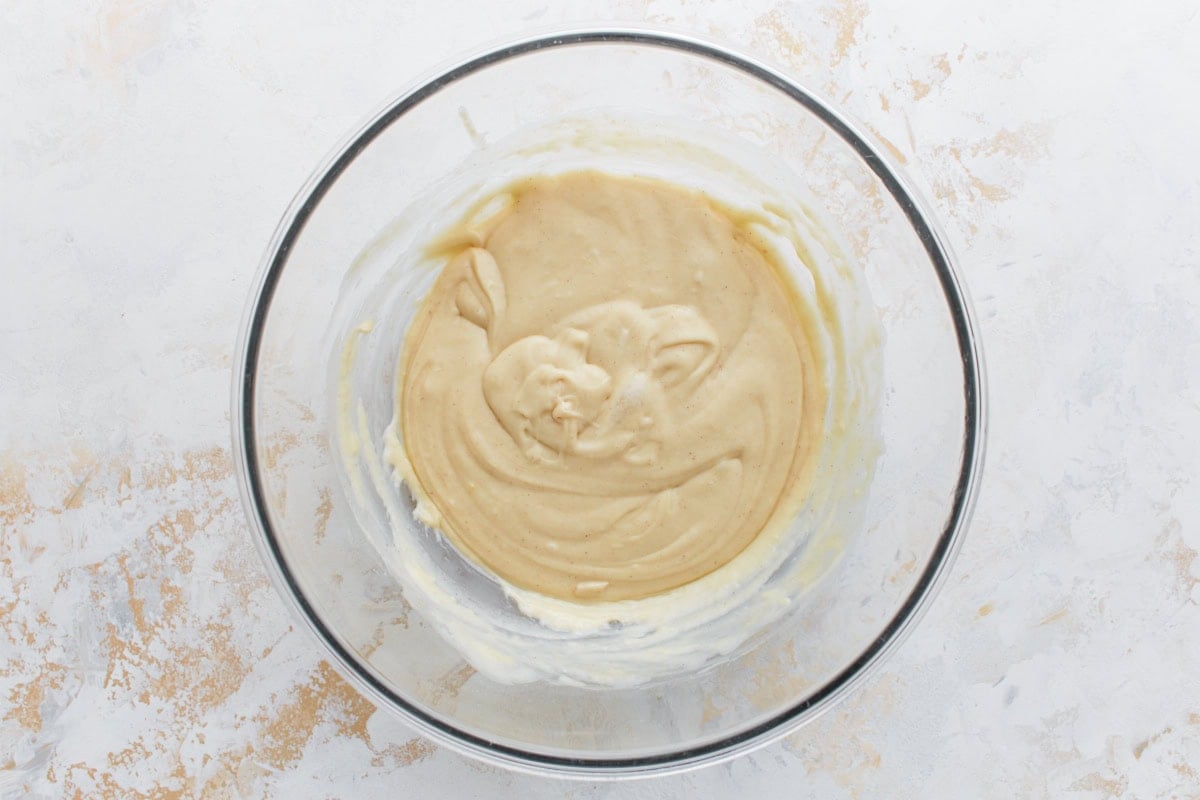 Fully mixed cinnamon roll muffin batter in a glass bowl, smooth and creamy in texture.