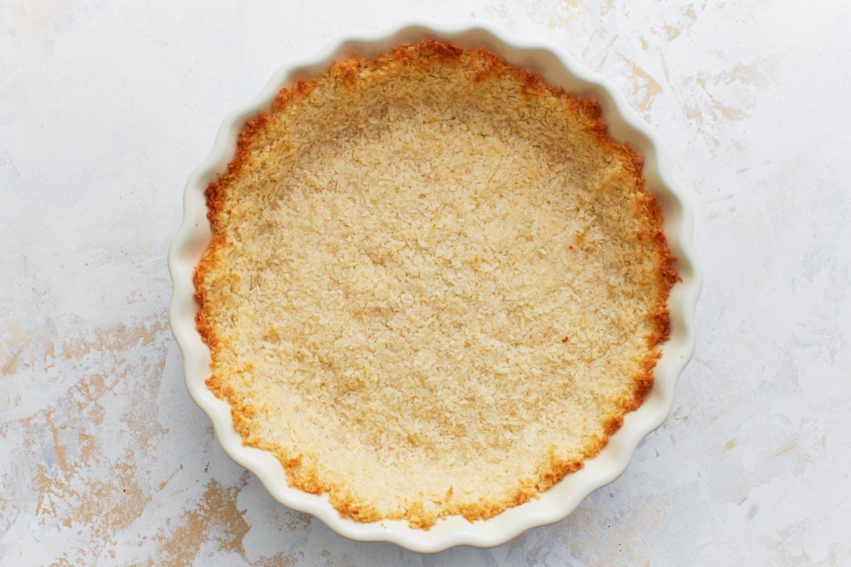 Baked coconut crust in a pie dish, golden brown around the edges.