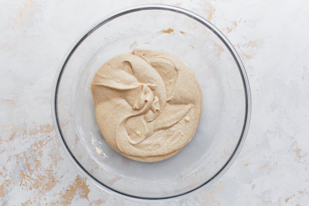 Thick, tan cupcake batter in a glass bowl, showing the texture before cocoa powder and boiling water are added.