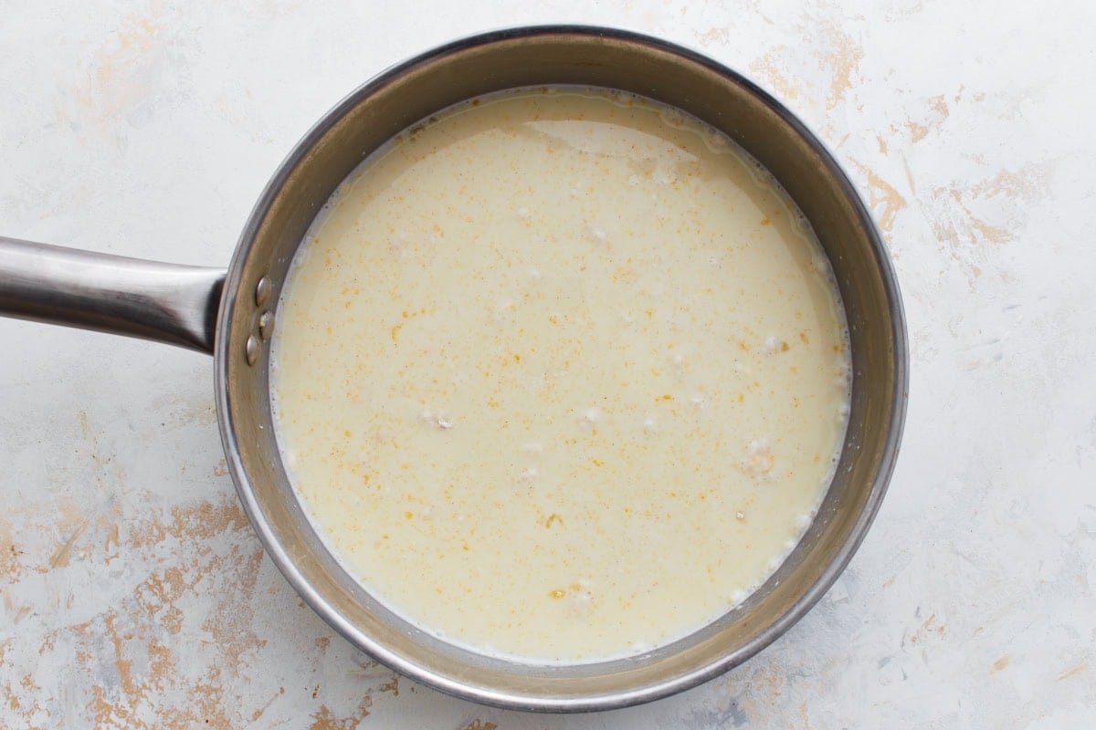 Custard ingredients in a saucepan before cooking, with visible egg yolks and milk.