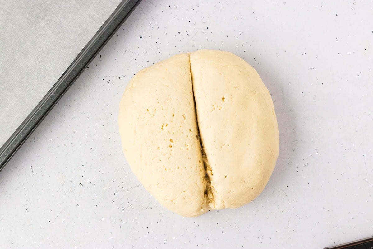 Dough ball split in half, ready to be divided further for shaping gluten-free breadsticks.