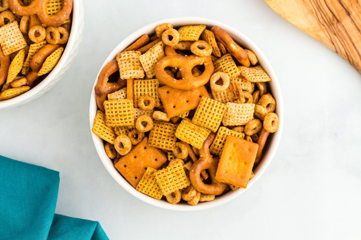 White bowl filled with gluten-free Chex Mix, highlighting the crunchy texture of cereal squares, mini pretzels, and crackers.