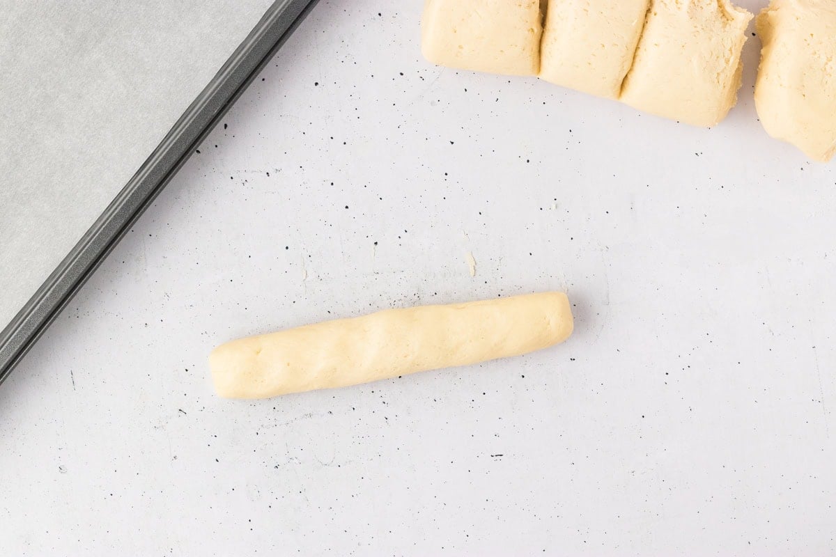 One dough portion shaped into a short log for forming a breadstick.