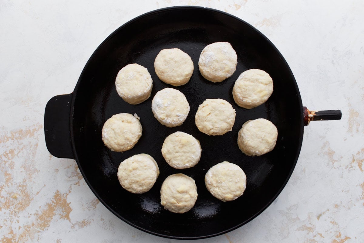 Raw gluten-free biscuit rounds arranged in a cast iron skillet before baking.