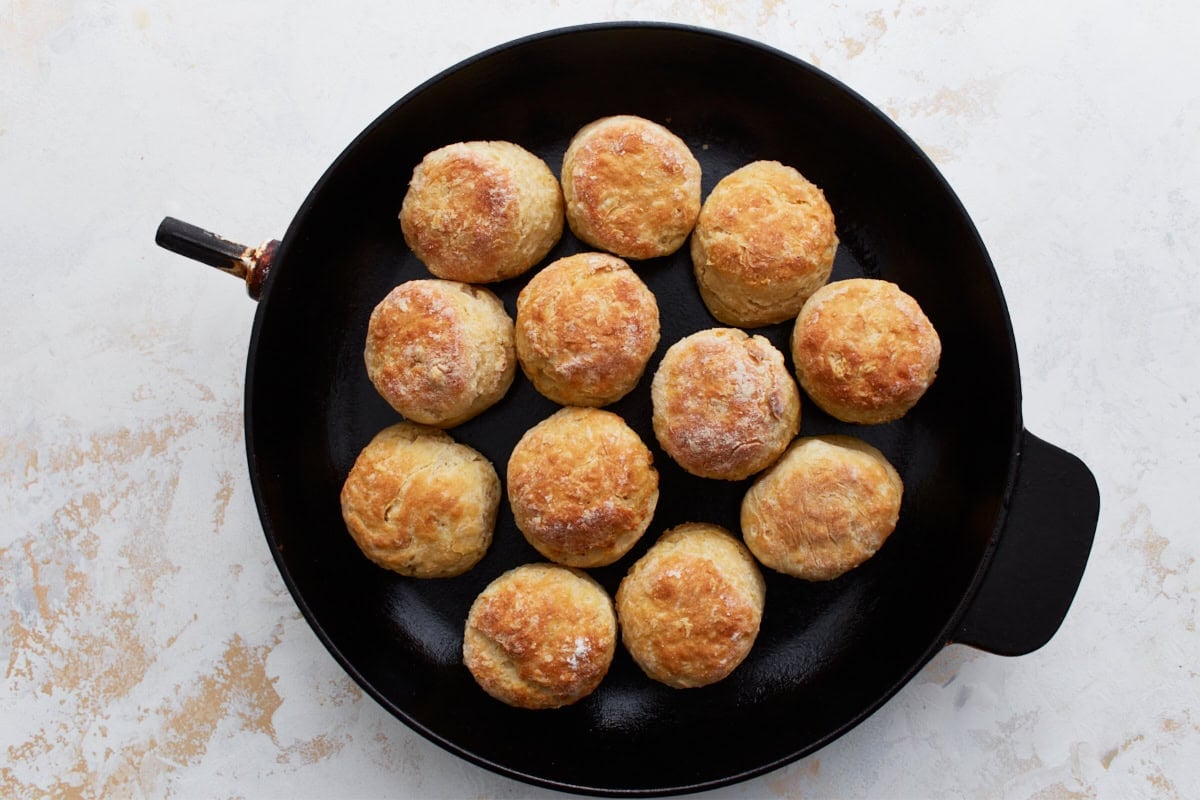 Freshly baked gluten-free buttermilk biscuits in a cast iron skillet, golden brown and puffed.