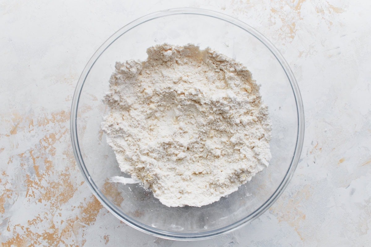 A clear mixing bowl with dry ingredients blended together for biscuit dough.
