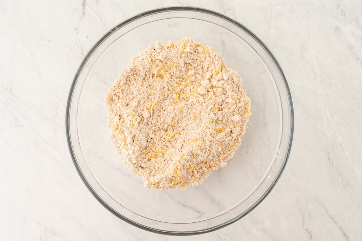The crumbly flour mixture with shredded cheddar cheese added and evenly distributed.