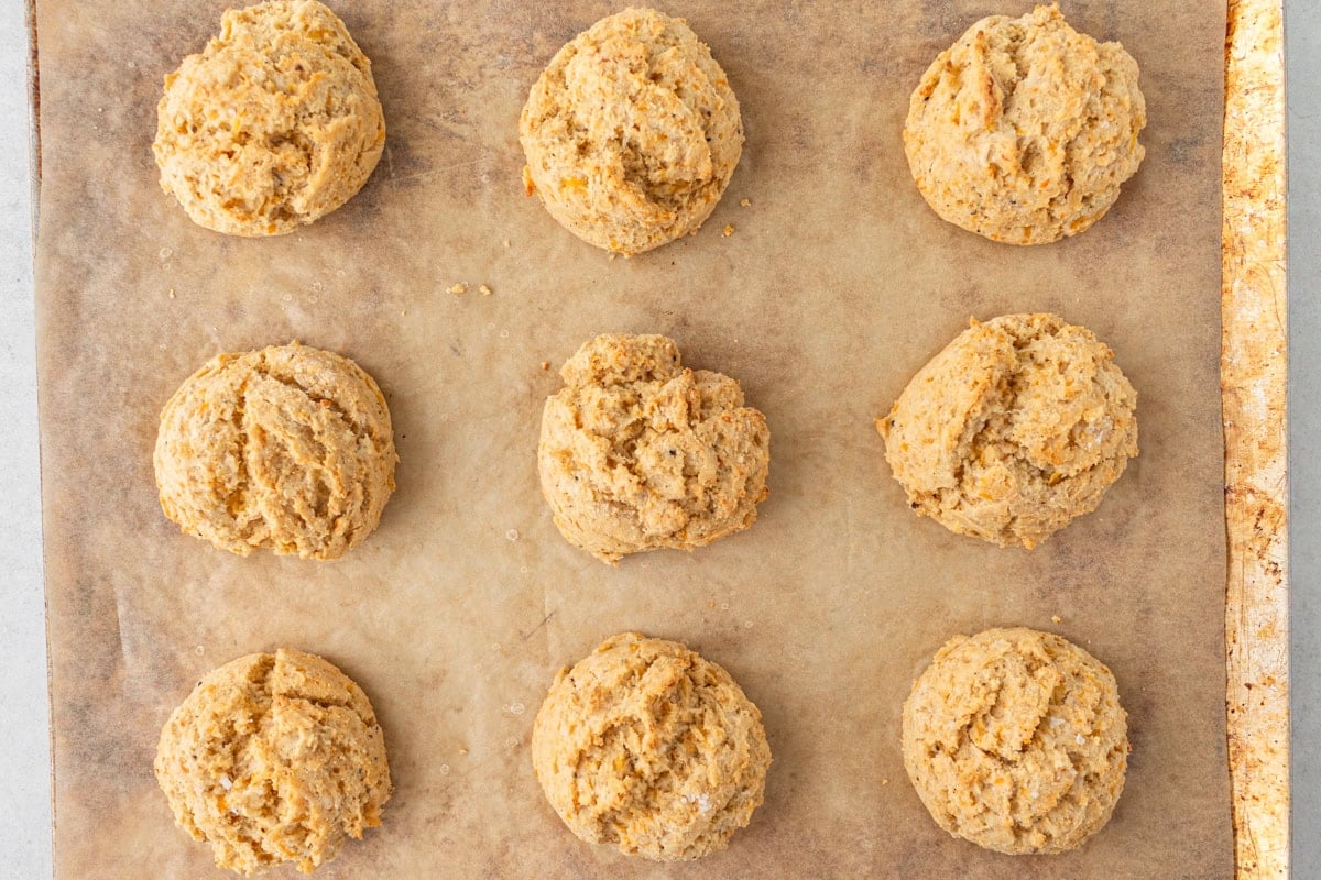 Freshly baked gluten-free cheddar biscuits on a baking sheet, golden and fluffy.