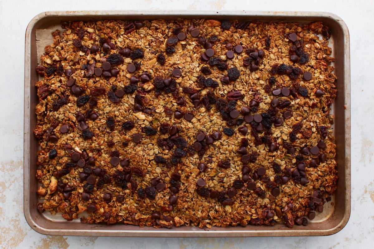 The baked granola topped with raisins and chocolate chips while still warm, pressed slightly into the surface.
