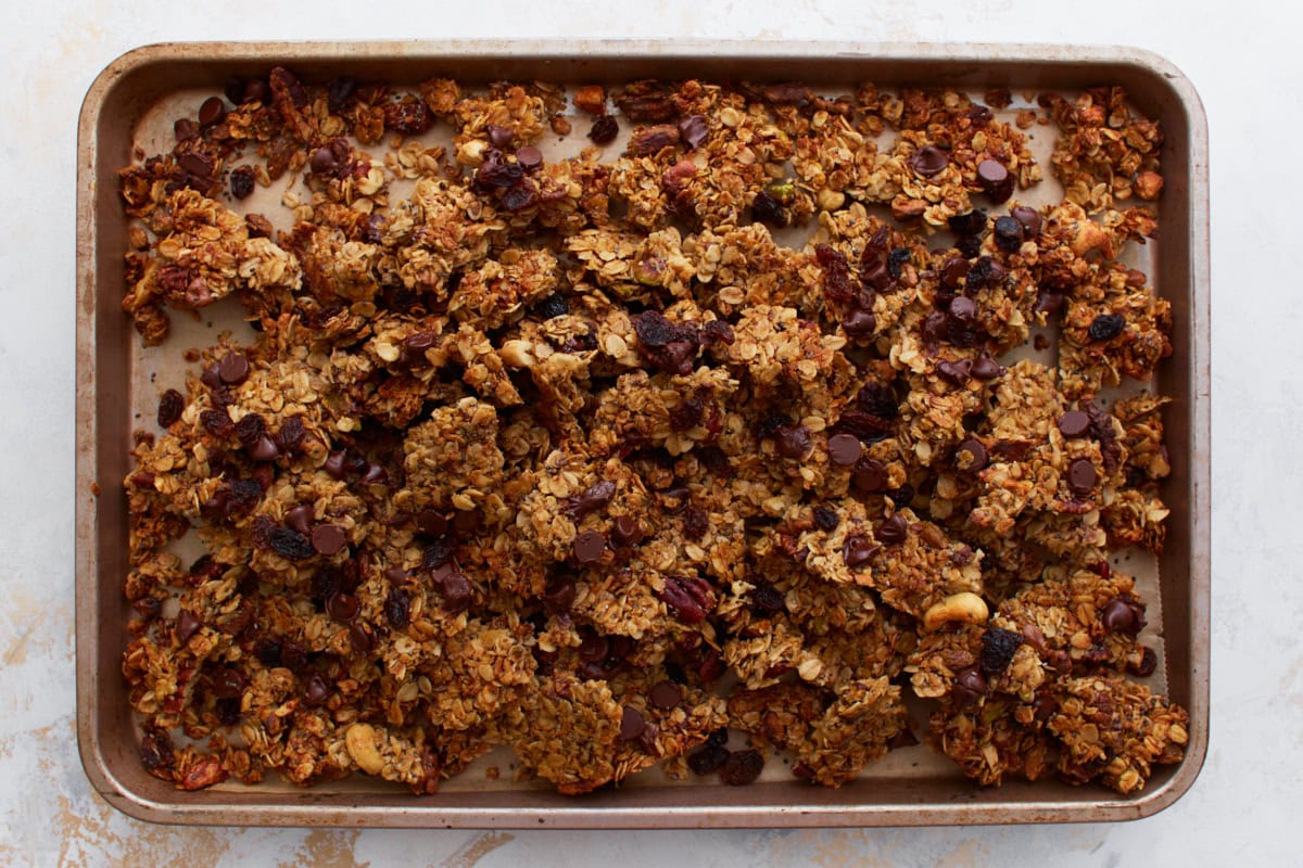 A zoomed-out view of the finished gluten-free granola, now broken into clusters and evenly scattered across the baking sheet.
