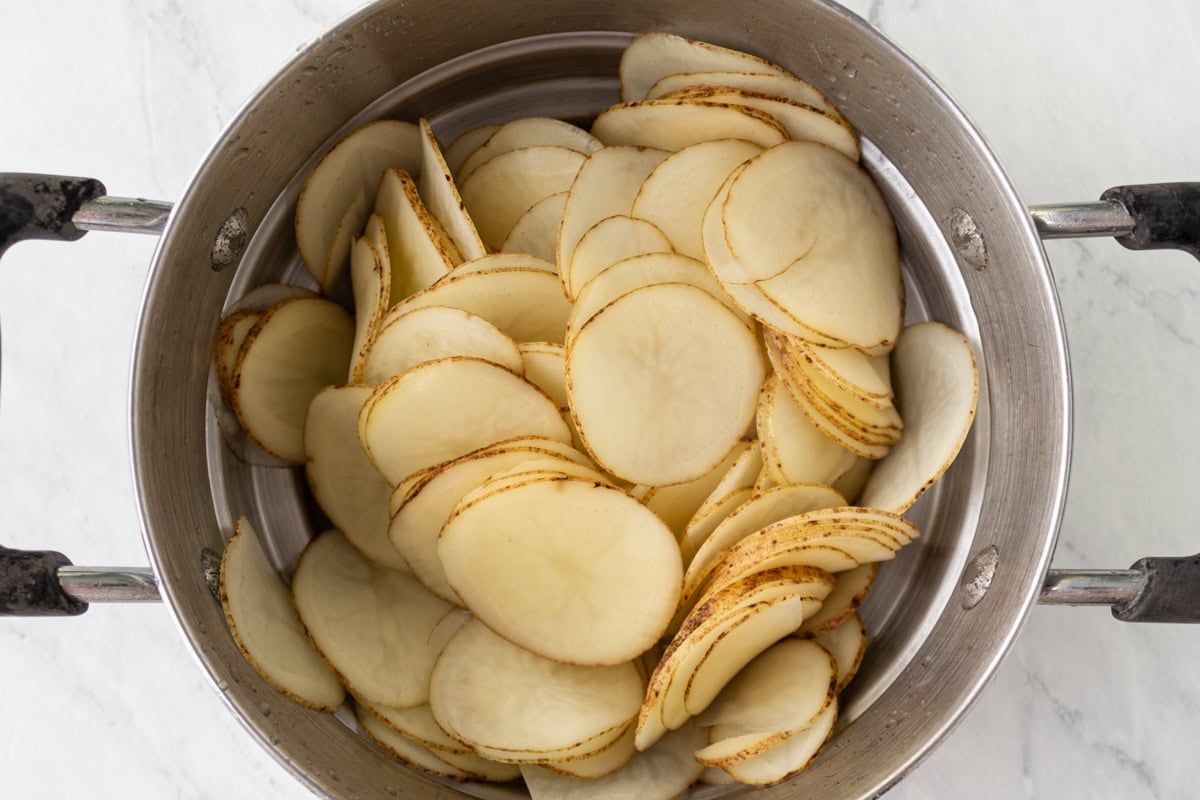 Drained and rinsed potato slices in a metal pot, prepped for drying.