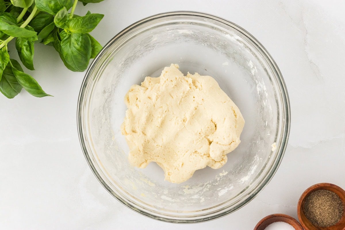 Ball of gluten-free pasta dough mixed and resting in a glass bowl