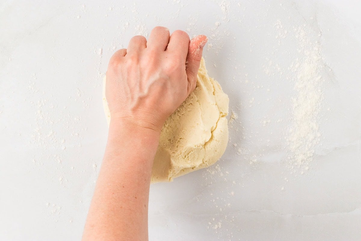 Hand kneading gluten-free pasta dough on a floured surface