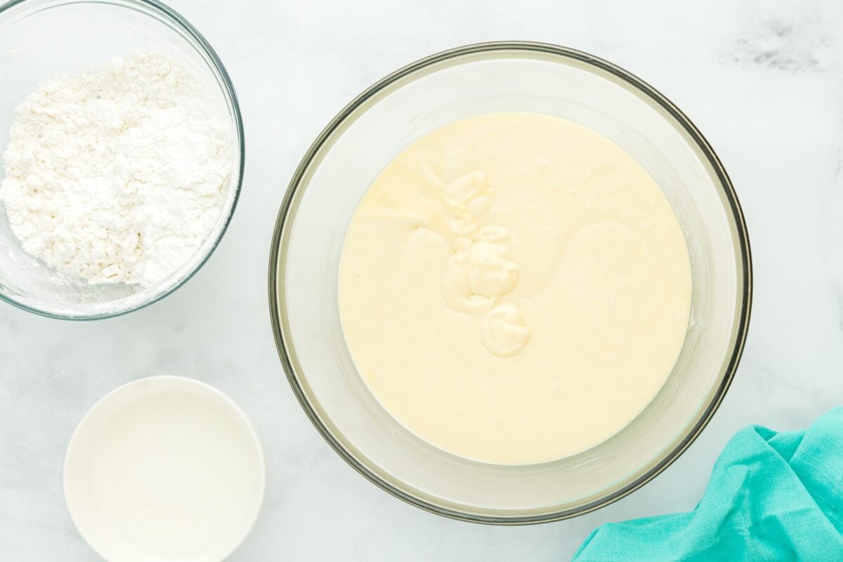 A bowl filled with pale, smooth gluten-free cake batter, ready for sprinkles.