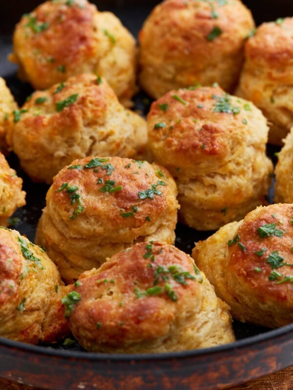 Freshly baked gluten-free cheddar bay biscuits in a cast iron skillet, topped with melted garlic butter and chopped parsley.