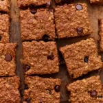 Close-up of sliced baked oatmeal bars with chocolate chips on a wooden surface, showing a golden-brown, chewy texture.