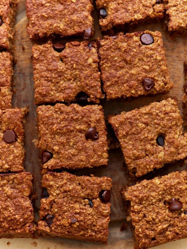 Close-up of sliced baked oatmeal bars with chocolate chips on a wooden surface, showing a golden-brown, chewy texture.