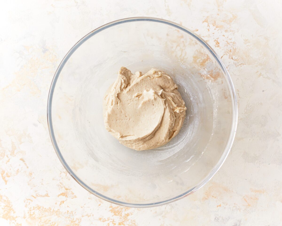 Soft, sticky dough for gluten-free pita bread in a glass mixing bowl after mixing wet and dry ingredients.