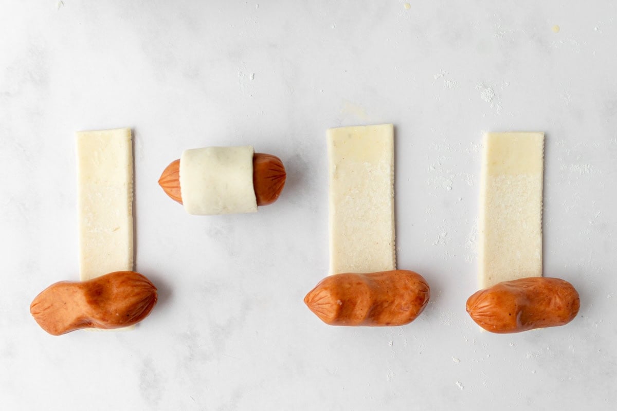 Step-by-step view of wrapping Lit’l Smokies in puff pastry strips on a floured surface.