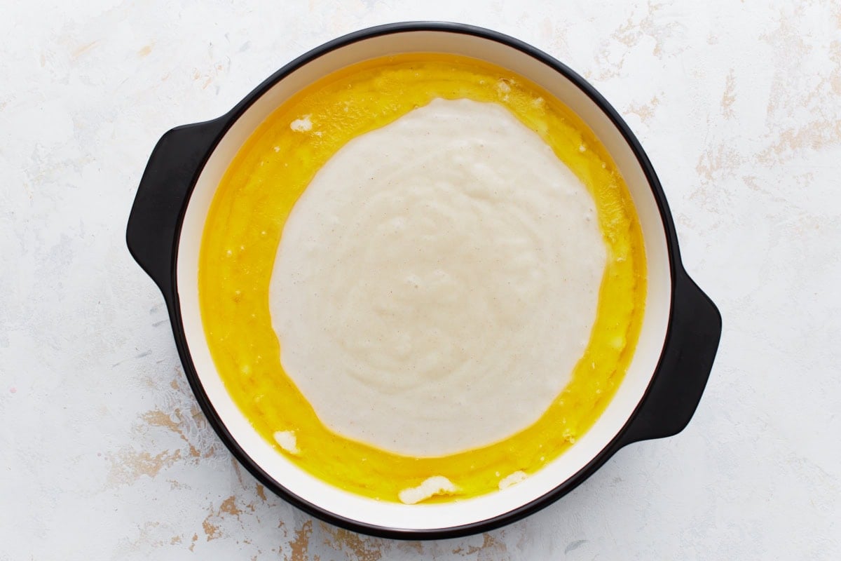Batter poured into the center of the baking dish, with melted butter around the edges.