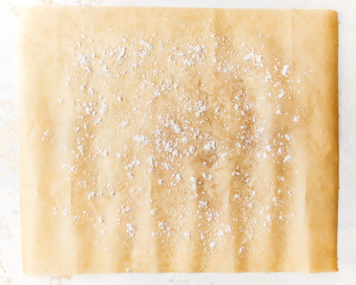 A piece of parchment paper sprinkled with gluten-free flour, ready for shaping pizza dough.