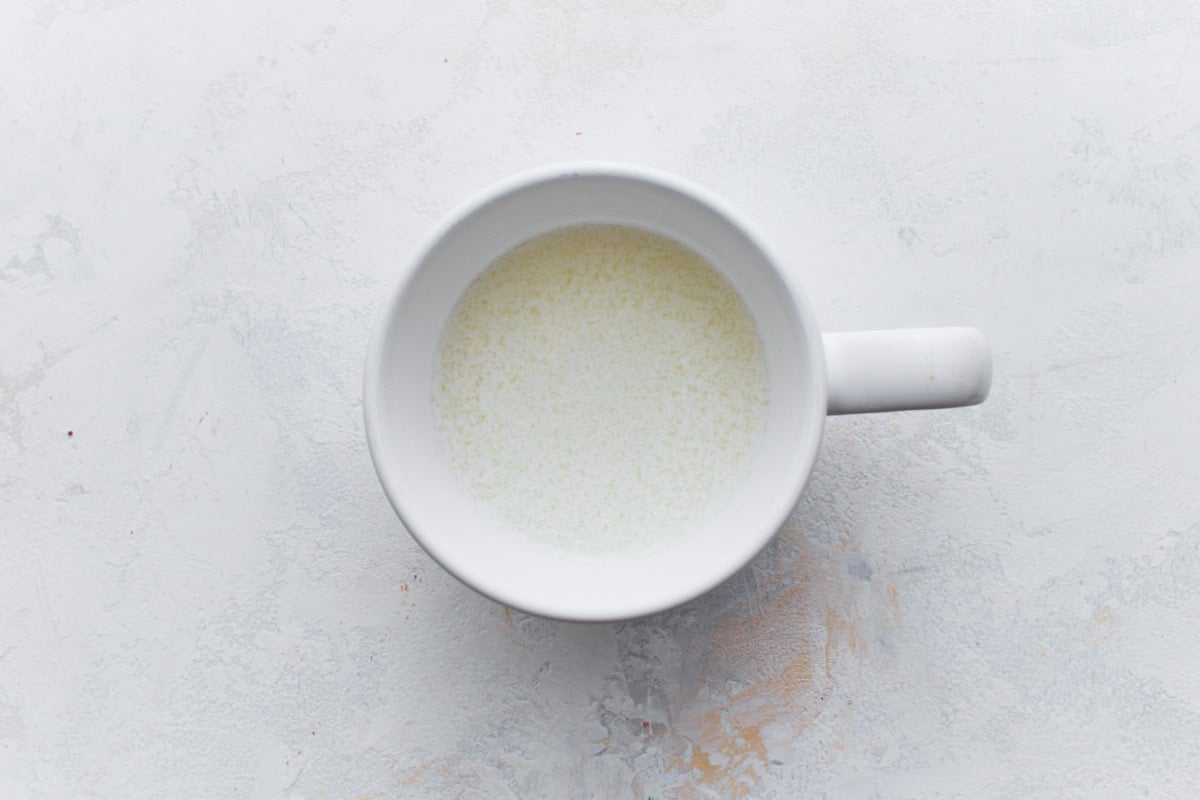 White mug filled with homemade buttermilk substitute on a light textured surface.