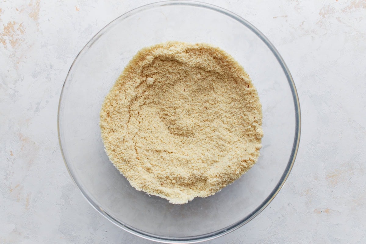 Glass bowl with almond flour and dry ingredients mixed together.