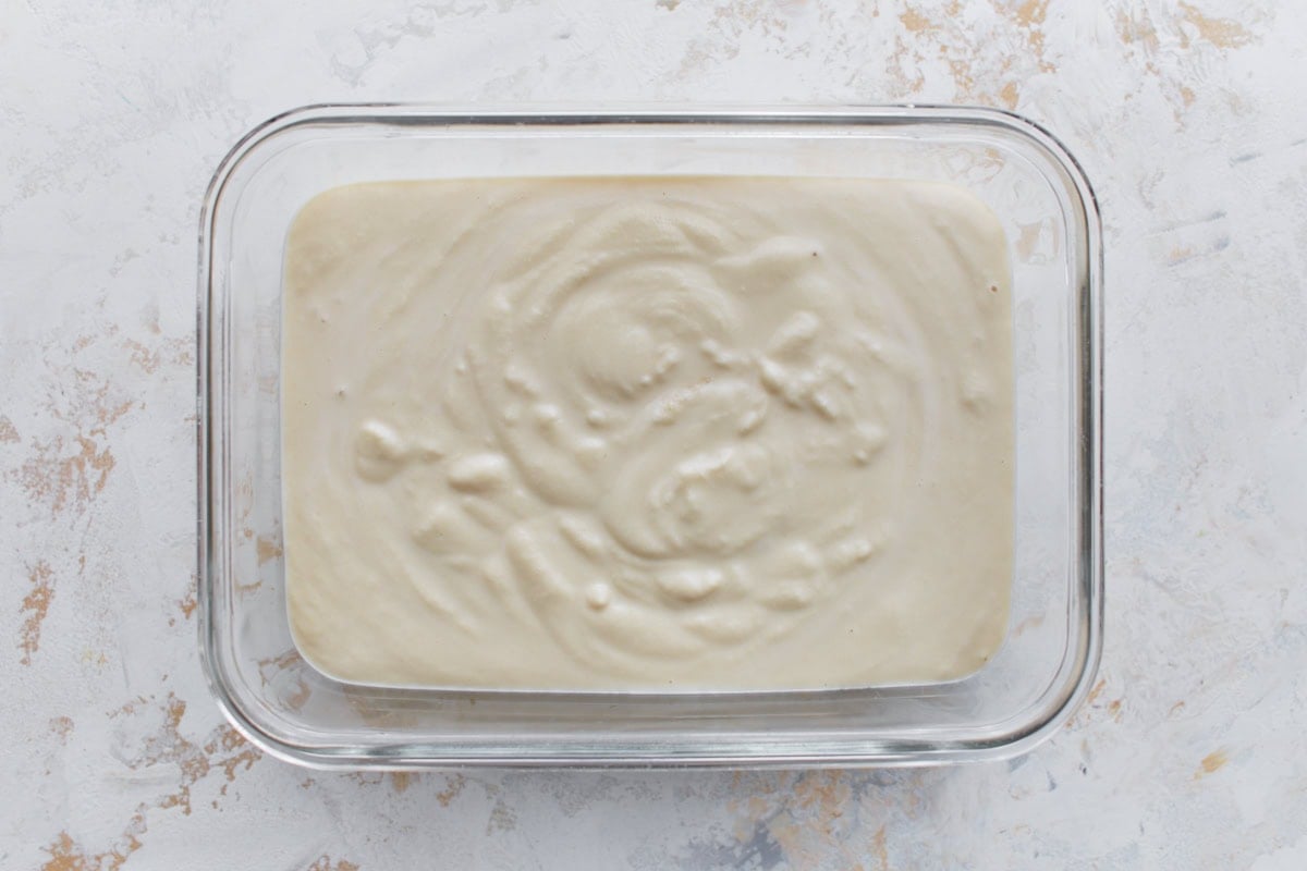 Glass container filled with freshly blended almond milk ice cream base before freezing.