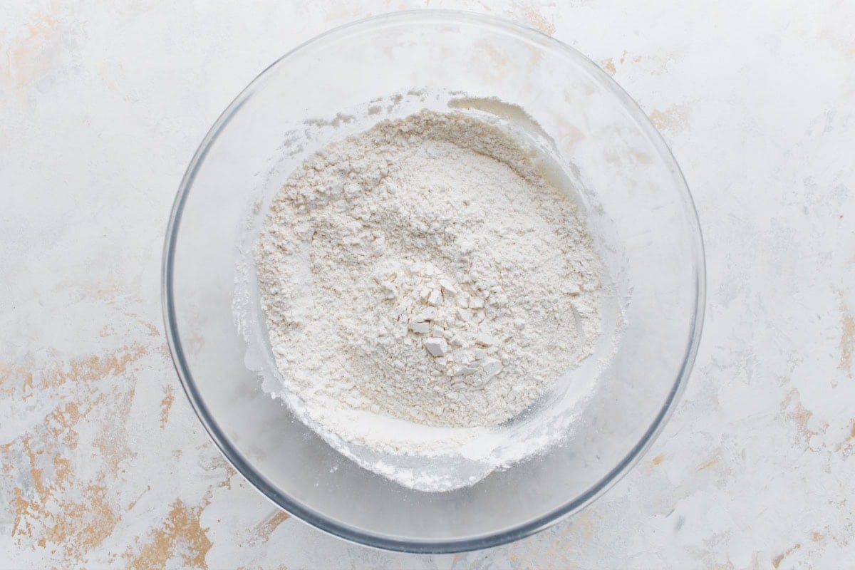 Overhead shot of gluten-free flour and dry baking ingredients combined in a large clear bowl.