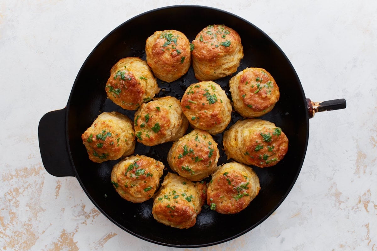 Freshly baked biscuits in a cast iron skillet glistening with garlic butter topping.