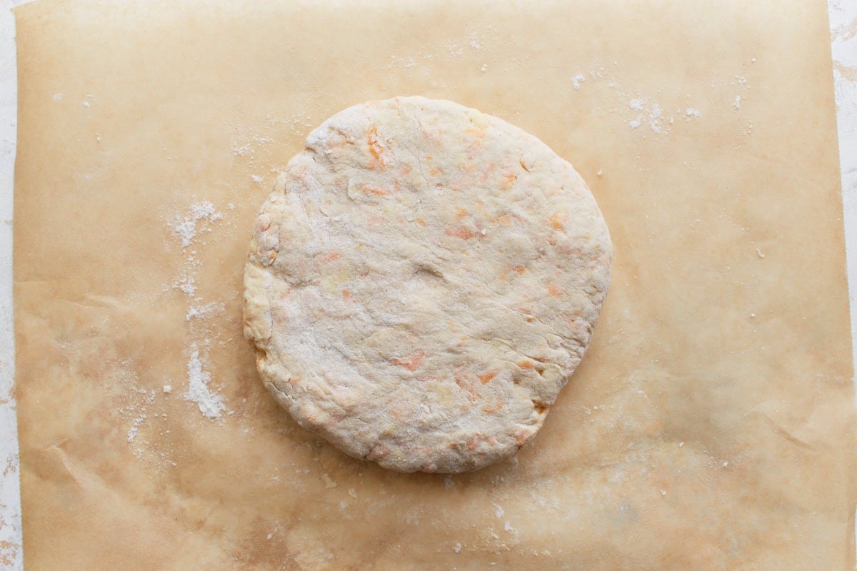 Biscuit dough formed into a thick, round disk, about 2 inches tall, prepped for cutting.