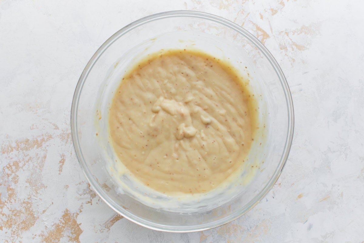 A bowl of creamy gluten-free soup mixture seasoned with spices for the top layer of the casserole.