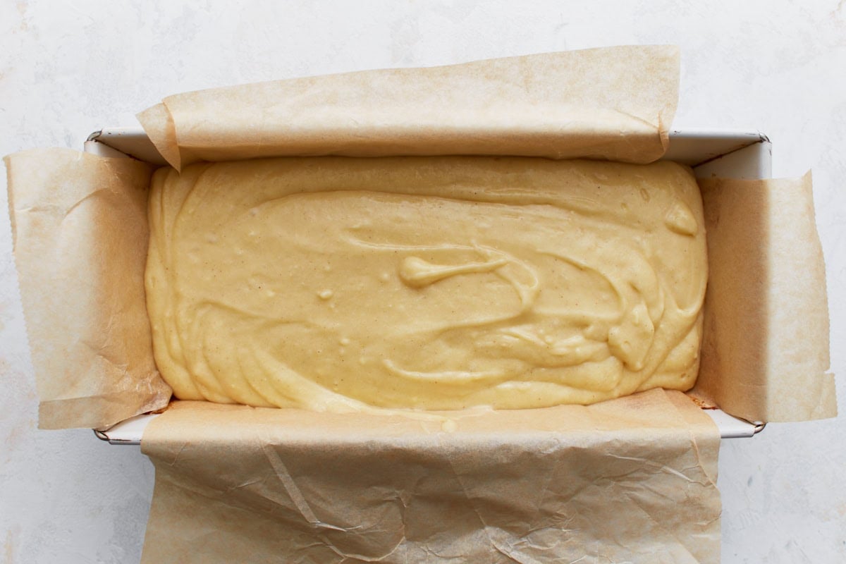 Lemon loaf batter poured into a parchment-lined loaf pan, ready for baking.