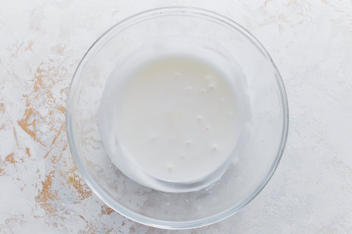 Lemon glaze mixture in a clear bowl, smooth and white.