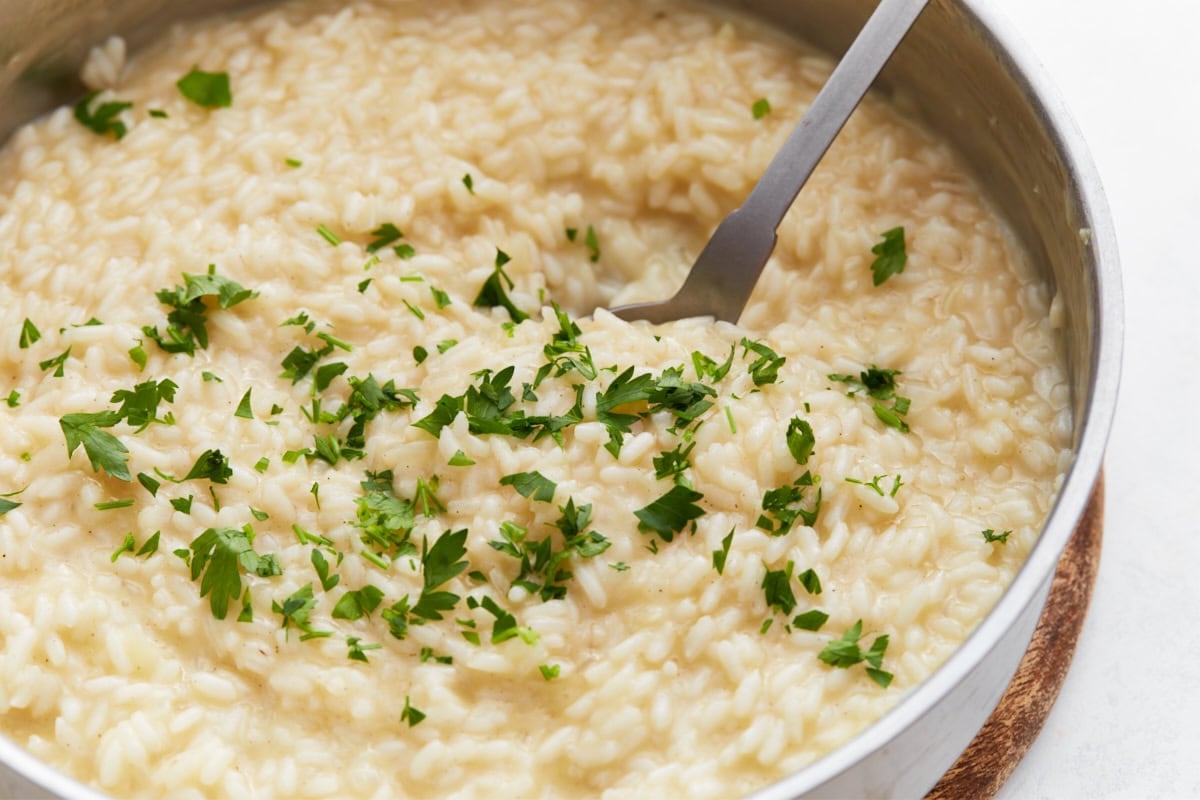 lose-up of creamy risotto with parsley on top and a spoon ready to serve.