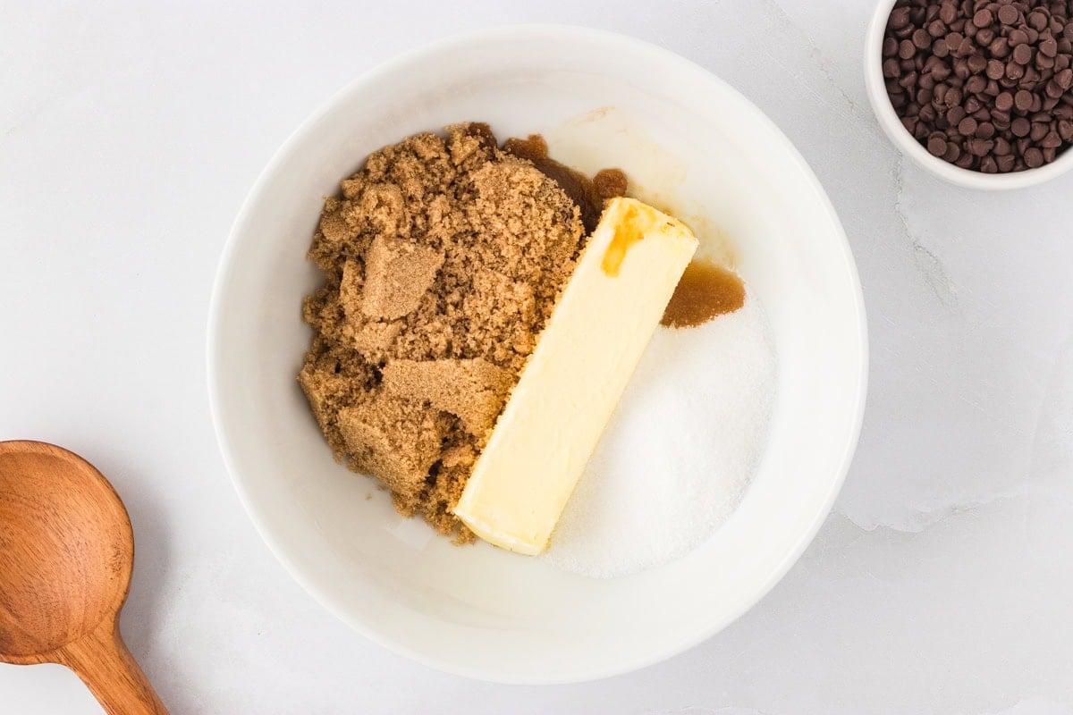 Mixing bowl with softened butter, brown sugar, granulated sugar, and vanilla extract ready to be creamed together.