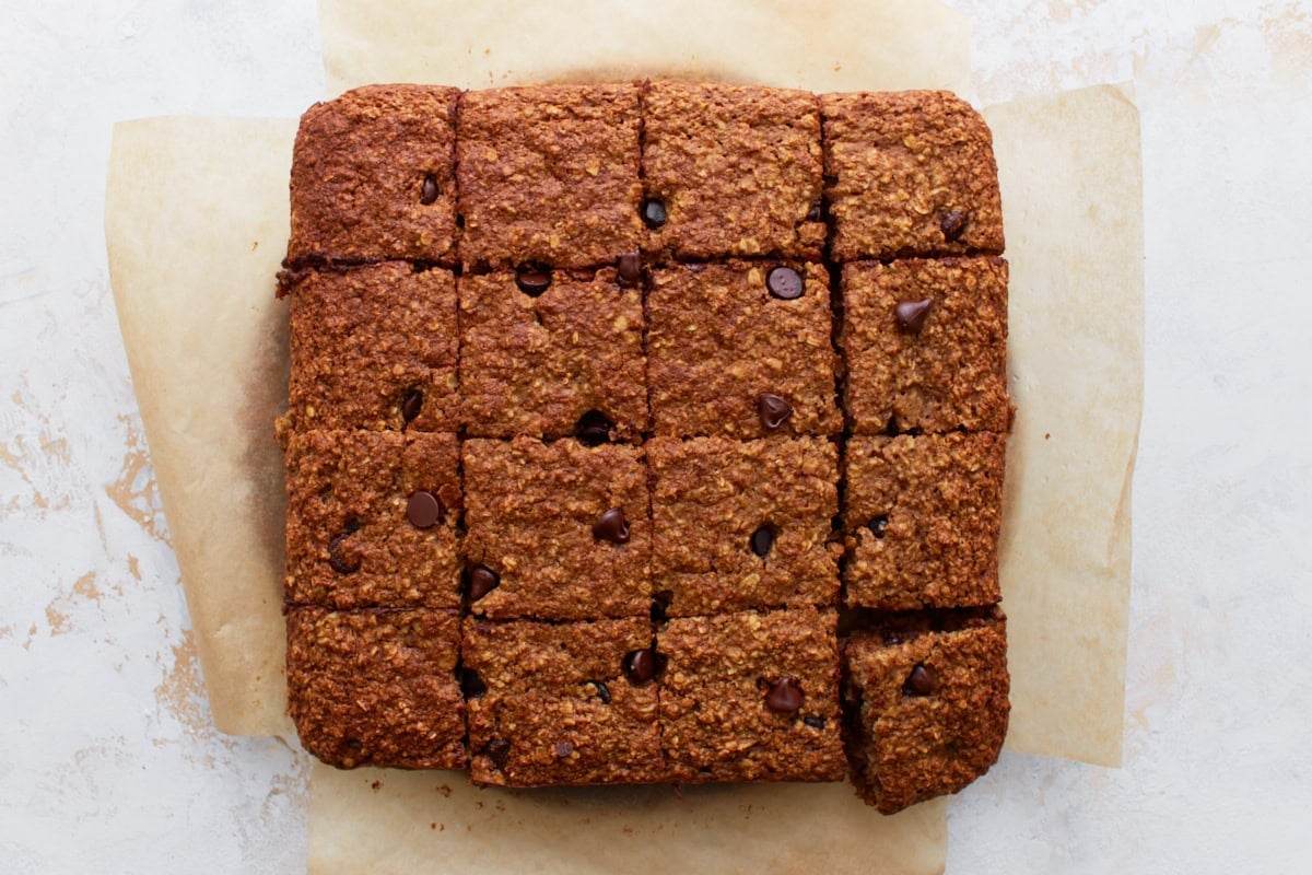 Baked oatmeal bars sliced into 16 even squares on parchment paper, ready to serve.