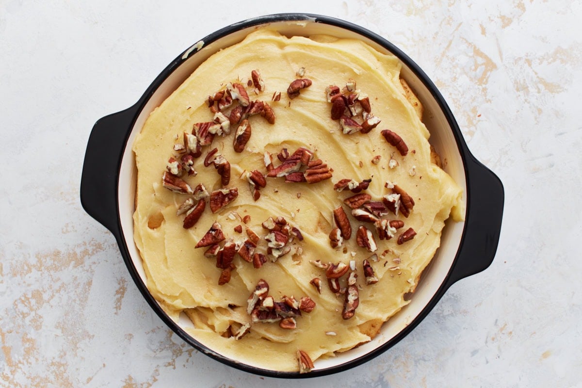 Batter spread over the apple layer in the baking dish and topped with chopped pecans before baking.