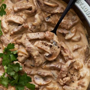 Close-up of creamy gluten-free beef stroganoff in a skillet, with tender beef strips, mushrooms, and a rich sauce, garnished with fresh parsley.