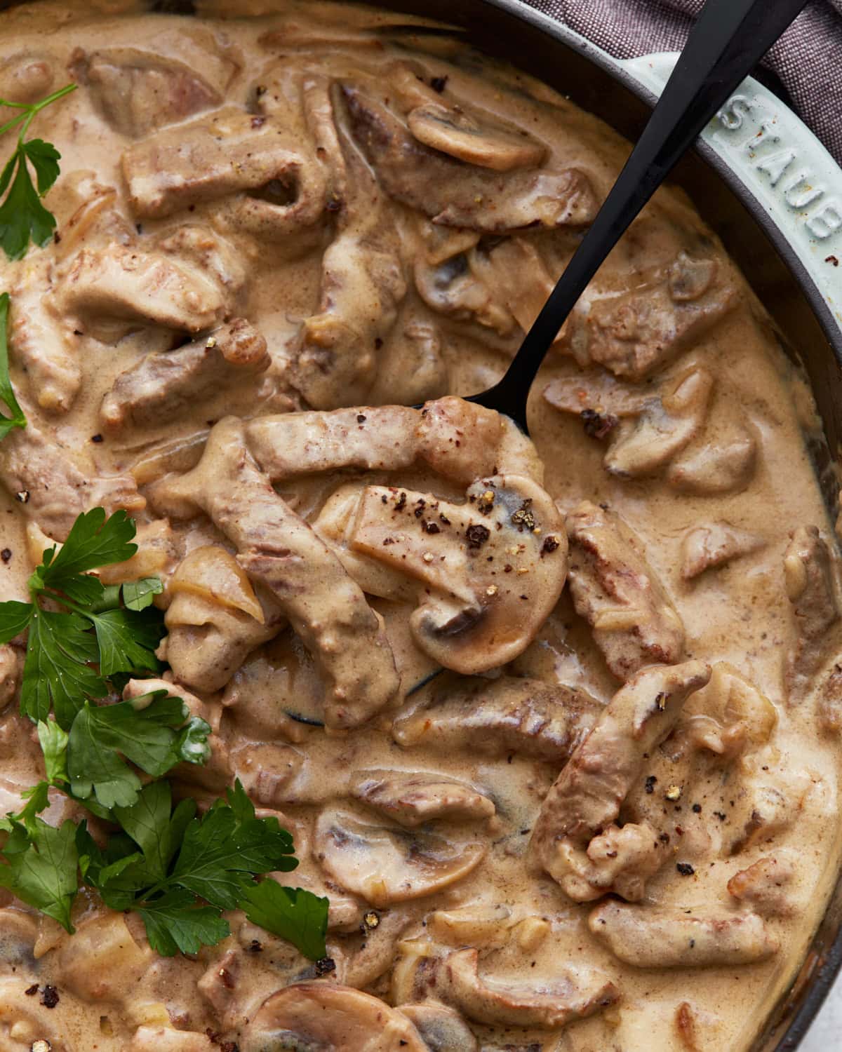 Close-up of creamy gluten-free beef stroganoff in a skillet, with tender beef strips, mushrooms, and a rich sauce, garnished with fresh parsley.