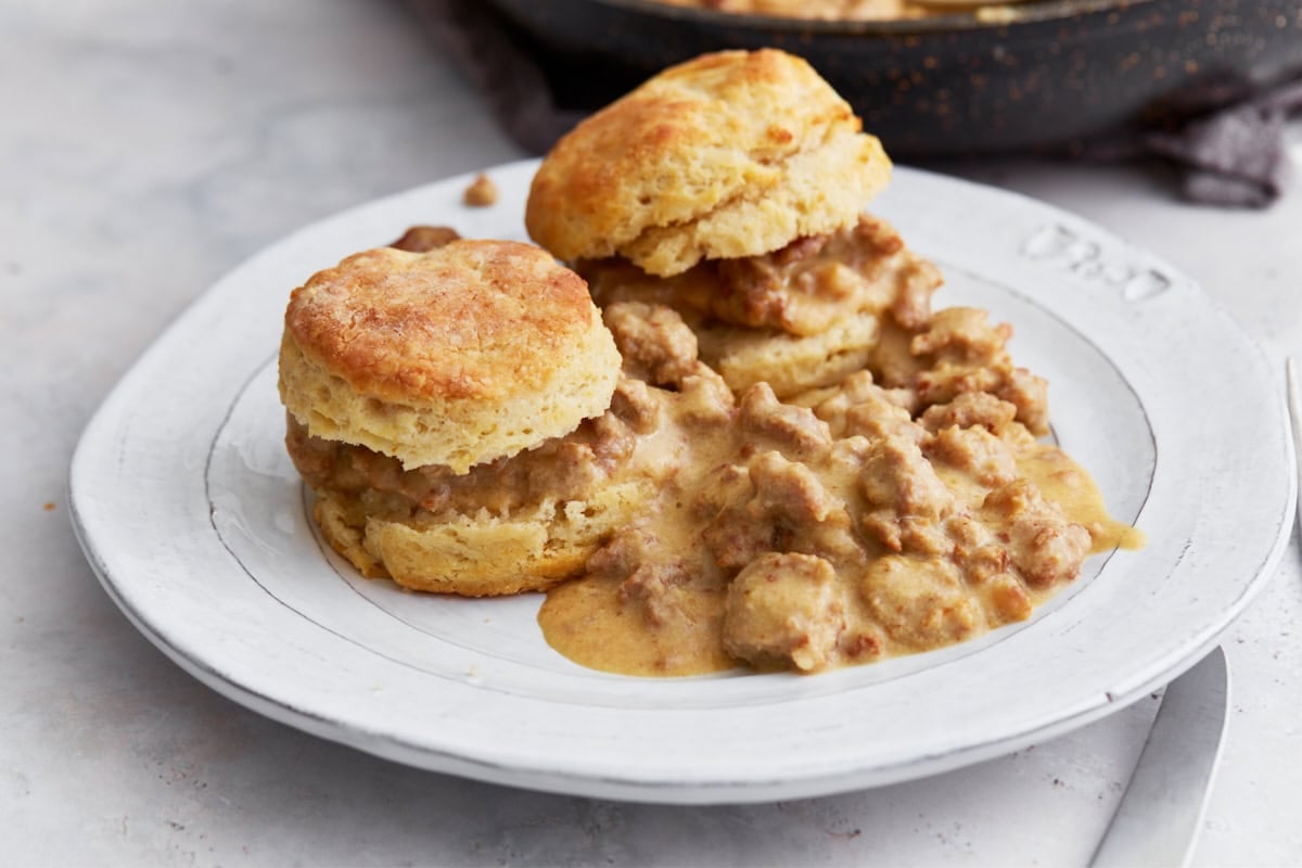 Flaky gluten-free biscuits topped with hearty sausage gravy, served on a white plate.