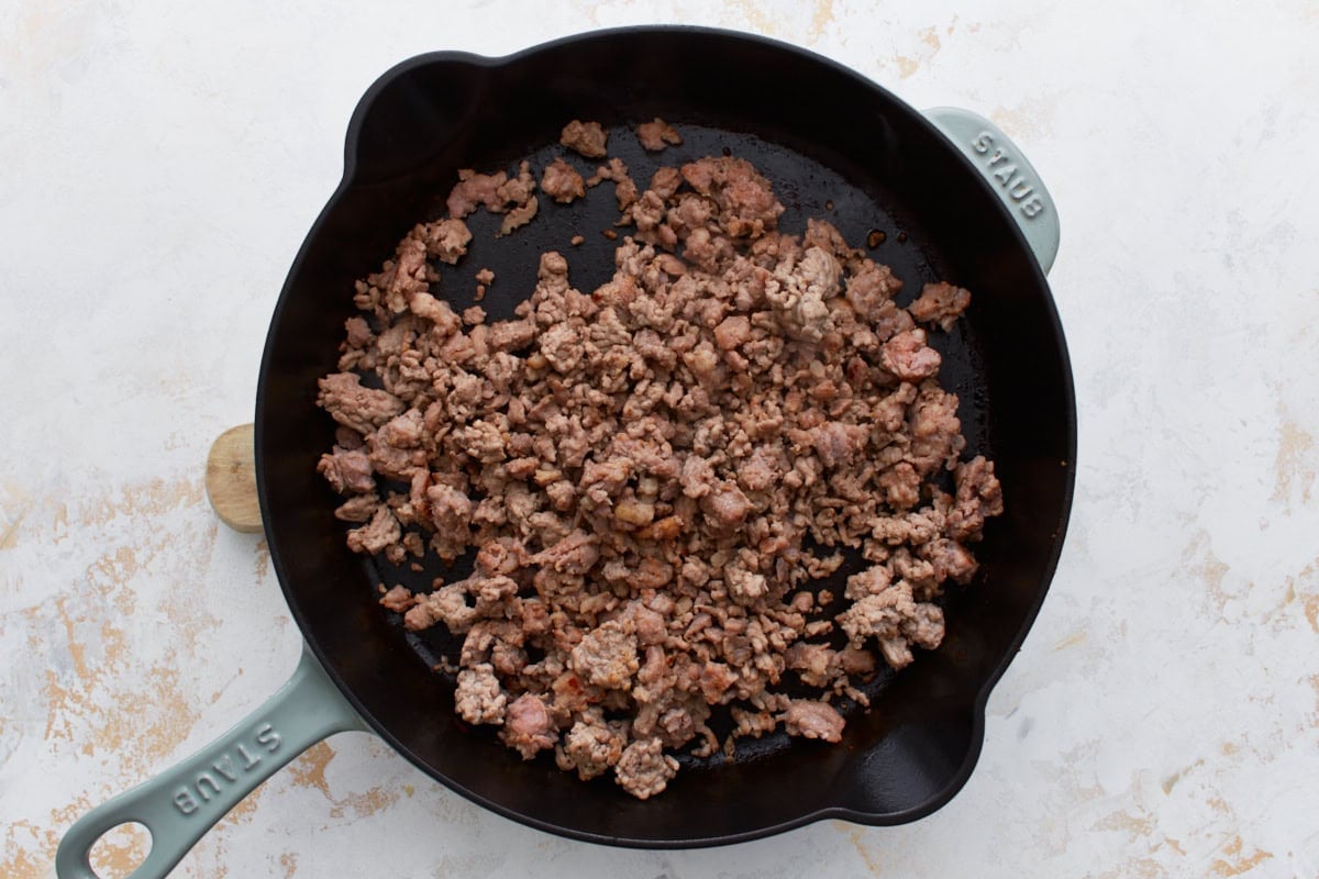Cooked ground sausage in a cast iron skillet, just browned and ready for the next step.