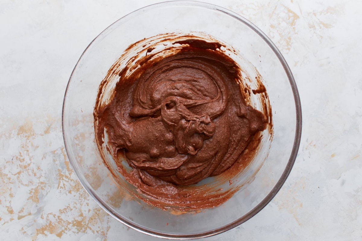 Keto brownie batter in a glass bowl with visible swirls and folded-in sugar-free chocolate chips.