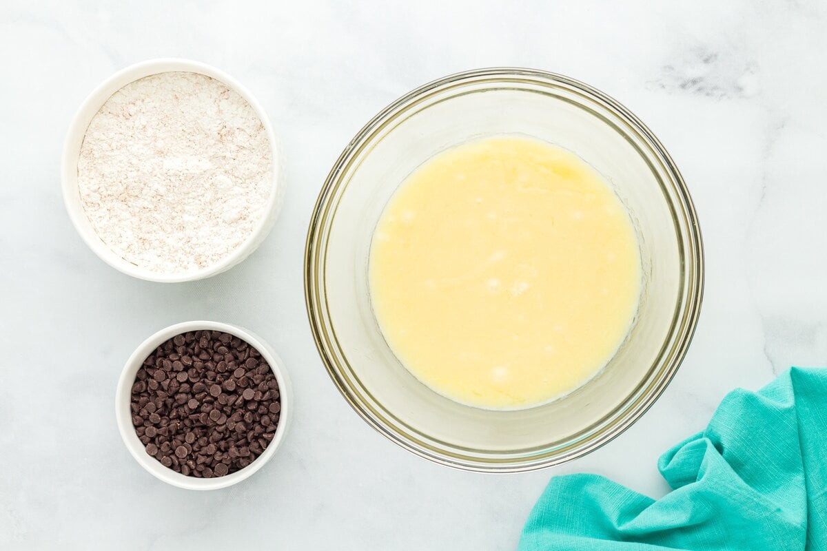 Overhead view of the separated muffin ingredients—gluten-free flour, mini chocolate chips, and a bowl of mixed wet ingredients.