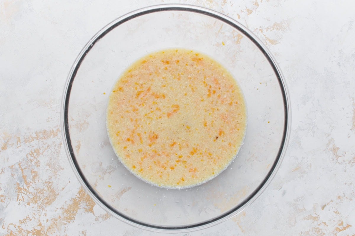 Egg and cheese mixture whisked together in a glass bowl.