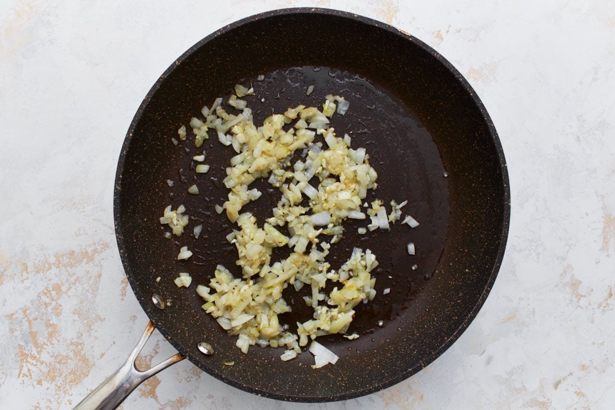 Chopped onions and garlic sautéing in a skillet.