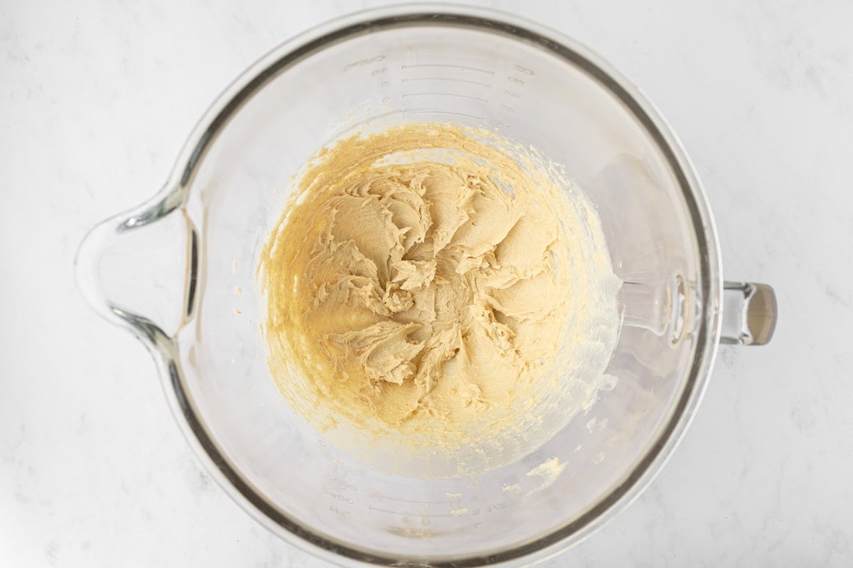 Mixing bowl filled with creamed butter and brown sugar for gluten-free animal cracker dough.