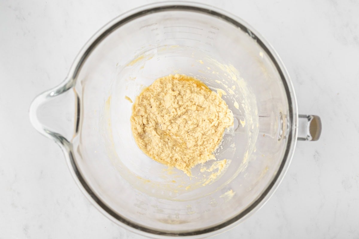 Mixing bowl with wet ingredients combined for gluten-free animal cracker dough, showing a slightly curdled texture.
