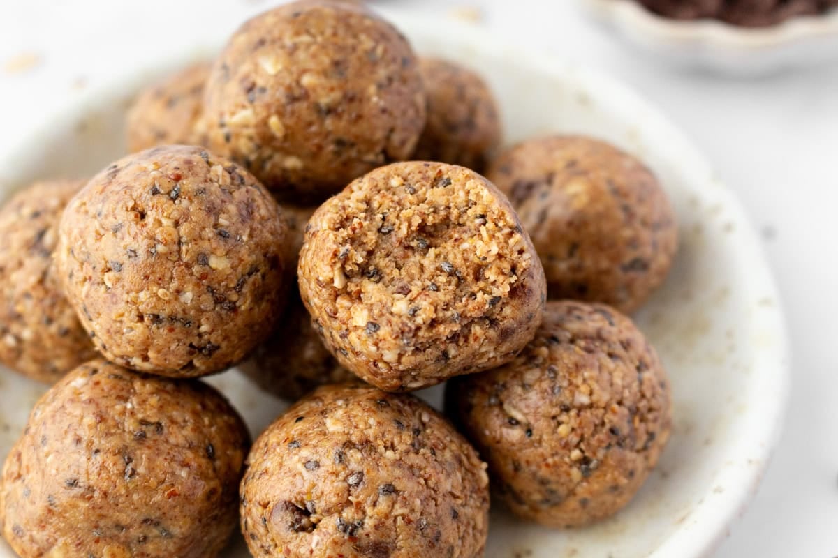 Close-up of a plate of gluten free protein balls, with one ball in front bitten open to reveal its chewy, textured center.