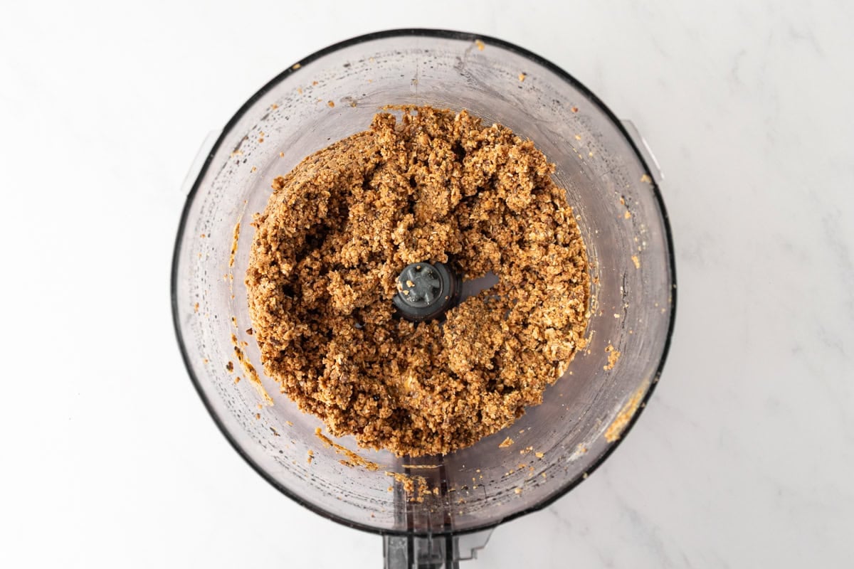 Overhead view of a food processor with a slightly looser, crumbly mixture for gluten free protein balls before rolling.